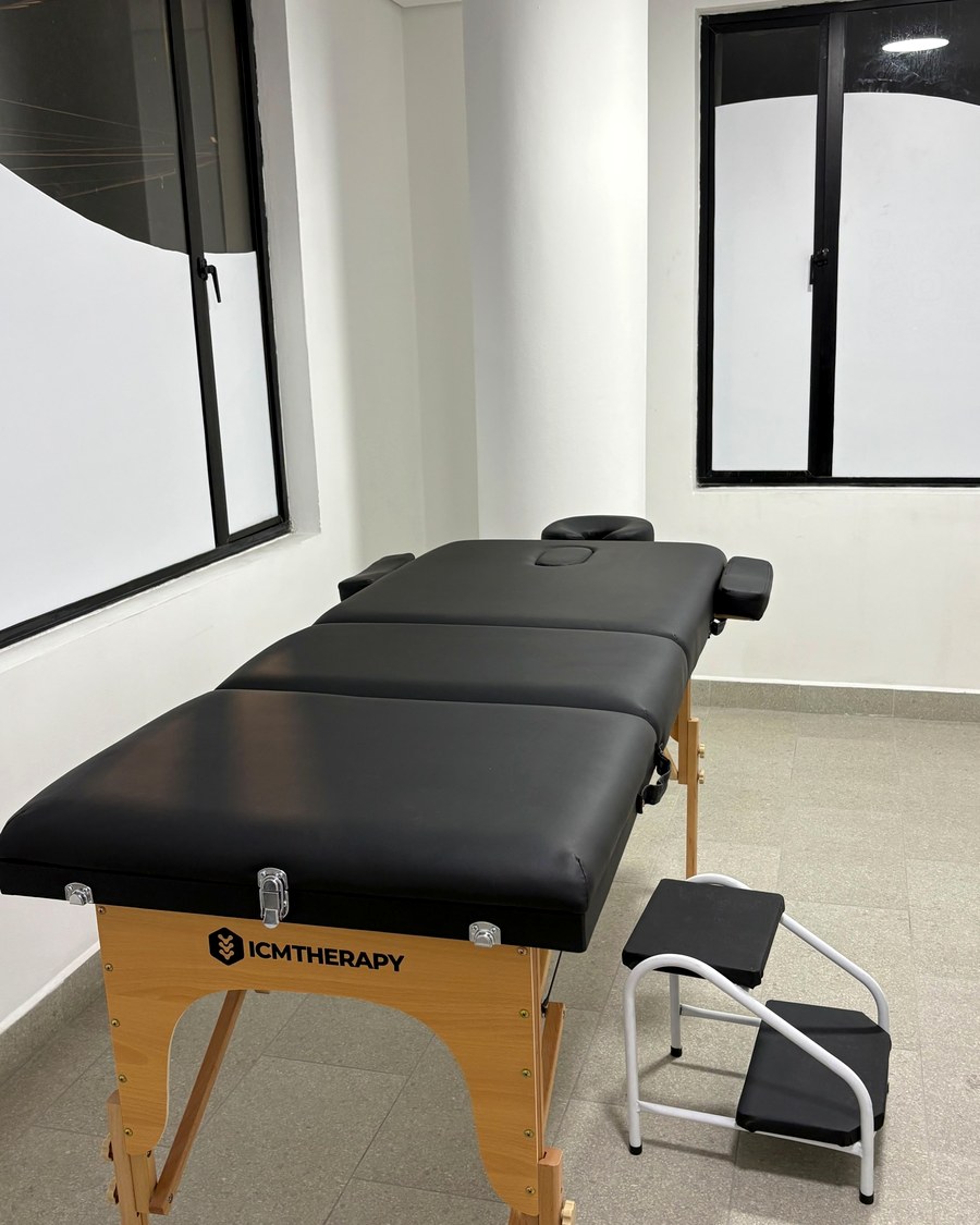 Sala de tratamiento con camilla, junto a las ventanas del consultorio